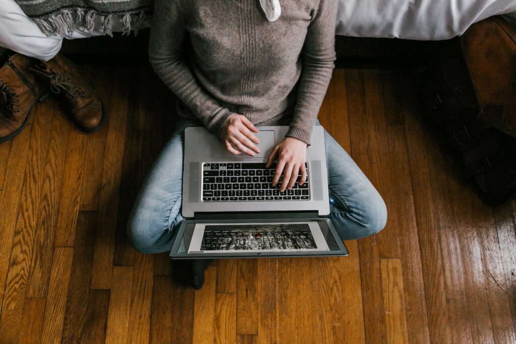 Person in Gray Long Sleeve Shirt Using Macbook Pro